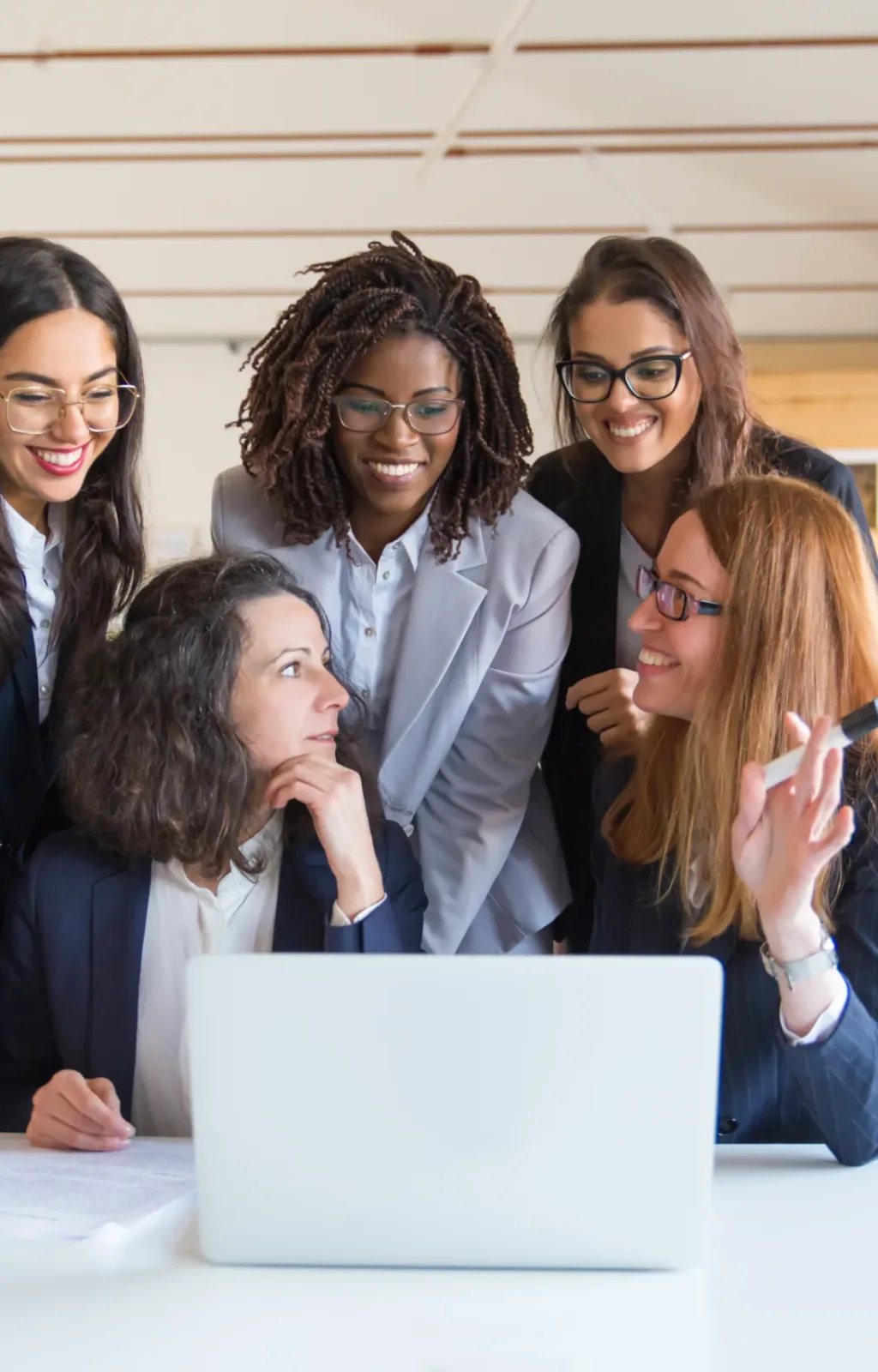 Content businesswomen working with laptop Content businesswomen working with laptop. Front view of cheerful multiethnic female colleagues using laptop computer and discussing work in office. Women in business concept